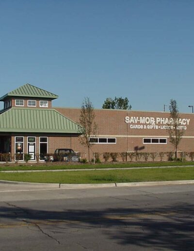 A single-story commercial building housing sav-mor pharmacy under a clear blue sky.