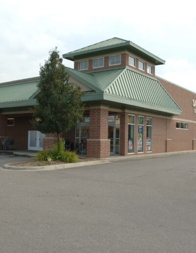 A single-story commercial building with a sign that reads "village pharmacy" and a black suv parked in front.