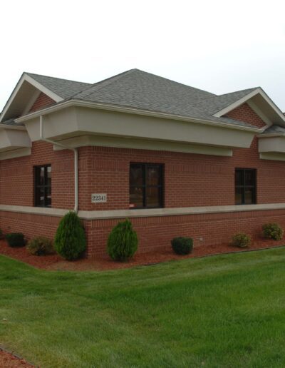 Single-story brick building with a hipped roof and a well-manicured lawn.
