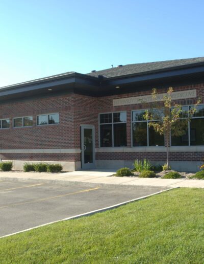 Modern single-story brick building with large windows and a parking lot.
